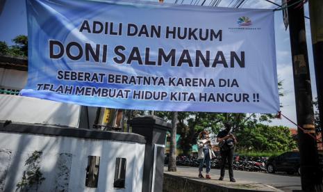 Warga berjalan di samping spanduk untuk terdakwa kasus penipuan investasi opsi biner Quotex Doni M. Taufik alias Doni Salmanan yang tengah menjalani sidang dakwaan di Pengadilan Negeri Bale Bandung, Baleendah, Kabupaten Bandung, Jawa Barat, Kamis (4/8/2022). Dalam sidang tersebut, Doni Salmanan didakwa meraih keuntungan sebanyak Rp4 miliar dari dugaan pencucian uang investasi aplikasi quotex. 