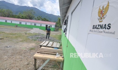 Warga berjalan di sekitar lokasi pengerjaan pembangunan hunian sementara (huntara) bantuan Badan Amil Zakat Nasional (Baznas) di Palu, Sulawesi Tengah, Senin (27/11/2018). 