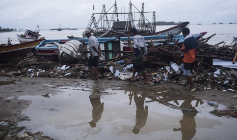 Warga berjalan di sisa-sisa bangunan dan kapal yang rusak diterjang tsunami Selat Sunda di Sumur, Pandeglang, Banten, Kamis (3/1/2019).