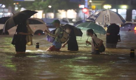  Warga berjalan di tengah banjir di selatan Seoul, Korsel, Senin (8/8/2022). Hujan deras mencapai 100 milimeter per jam, alias terderas dalam 80 tahun, telah melumpuhkan Seoul dan sekitarnya akibat banjir. Selebritas Korsel pun berlomba menyalurkan donasinya.