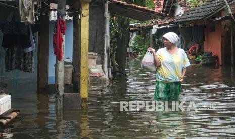 Warga berjalan melewati banjir di Tirto, Pekalongan, Jawa Tengah, Senin (7/2/2022). Berdasarkan data Badan Penanggulangan Bencana Daerah (BPBD) Kota Pekalongan, banjir akibat hujan deras pada Sabtu (5/2) dan Minggu (6/2) membuat sejumlah wilayah di Kota Pekalongan tergenang banjir dengan ketinggian antara 10-50 centimeter. 