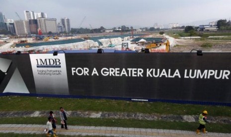 Warga berjalan melewati logo 1Malaysia Development Berhad (1MDB) di Kuala Lumpur, Malaysia.