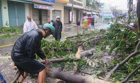 Warga berjalan melewati pohon yang tumbang akibat topan Damrey, di Nha Trang, Khanh Hoa, 4 November 2017. Topan ini menyebabkan 11 orang tewas