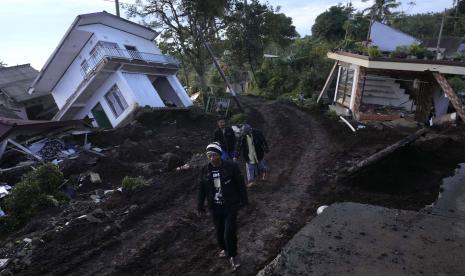 Warga berjalan melewati rumah-rumah yang hancur akibat gempa Senin di Cianjur, Jawa Barat, Indonesia, Kamis, 24 November 2022. Gempa berkekuatan 5,6 skala Richter menyebabkan ratusan orang tewas, luka-luka, dan hilang saat bangunan runtuh dan ketakutan warga berlarian menyelamatkan diri di pulau utama Indonesia dari Jawa. 