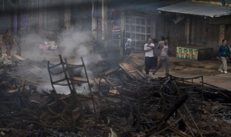  Warga berjalan melintasi bangunan yang terbakar yang menampung sebuah panti asuhan untuk anak-anak Muslim di Lashio, Myanmar, Kamis (30/5).     (AP/Gemunu Amarasinghe)