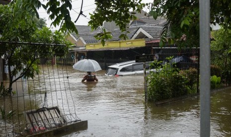 Warga berjalan melintasi banjir di perumahan Taman Narogong Indah, Bekasi, Jawa Barat, Rabu (1/1/2020). Hujan lebat sepanjang malam tahun baru yang mengguyur Bekasi dan kawasan sekitarnya mengakibatkan banjir terjadi di sejumlah titik. 