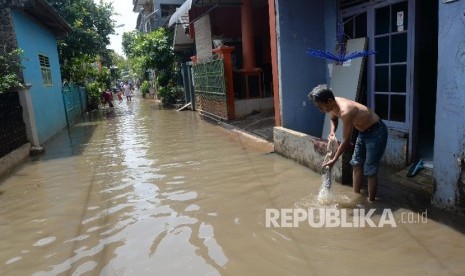 Warga berjalan melintasi genangan air saat banjir di permukiman warga di kawasan Cipinang Melayu, Jakarta Timur.