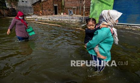 Warga berjalan melintasi jalan yang terendam banjir di Desa Prampelan, Kecamatan Sayung, Demak, Jawa Tengah, Kamis (11/2/2021). Meskipun banjir mulai surut, tapi sekitar 8.346 rumah warga yang tersebar di delapan desa di kecamatan tersebut masih terendam banjir dengan ketinggian bervariasi antara sekitar 20 cm - 1 meter akibat luapan Sungai Dombo Sayung dan sejumlah anak sungai di wilayah hilir pantura. 