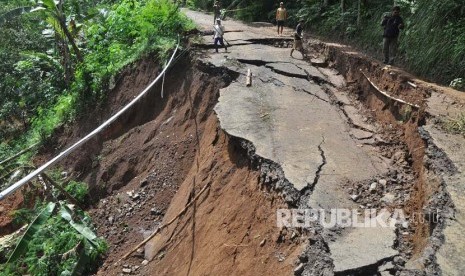 Warga berjalan melintasi lokasi jalan antar kecamatan yang longsor di Selomanik, Kaliwiro, Wonosobo, Jateng, Selasa (30/1).