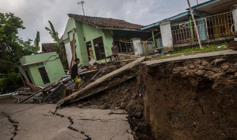 Warga berjalan melintasi rumah yang rusak akibat pergerakan tanah di Desa Cilangkap, Lebak, Banten, Sabtu (11/6/2022). Berdasarkan data BPBD Kabupaten Lebak sedikitnya lima rumah rusak dan akses jalan penghubung antardesa terputus akibat adanya bencana pergerakan tanah yang disebabkan tingginya intensitas hujan selama beberapa hari di daerah tersebut. Warga Lebak Diminta Waspada Curah Hujan Tinggi Sebabkan Bencana Alam