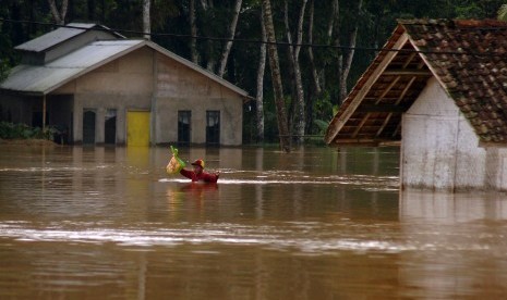 Warga berjalan menembus banjir akibat tanggul sungai jebol di Desa Tanjungsari, Kabupaten Tasikmalaya, Jawa Barat, Kamis (17/3). 