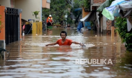 Warga berjalan menembus banjir di Kelurahan Cipinang Melayu, Kecamatan Makassar, Jakarta, Selasa (21/2).