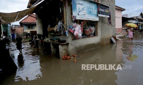  Warga berjalan menembus genangan air akibat banjir.