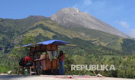 Warga berjualan makanan di tepi jalan dengan latar belakang Gunung Merapi di Jrakah, Selo, Boyolali, Jawa Tengah, Jumat (17/7/2020). Berdasarkan data pengamatan Balai Penyelidikan dan Pengembangan Teknologi Kebencanaan Geologi pada tanggal 16 Juli 2020 terjadi aktivitas kegempaan Gunung Merapi sebanyak empat guguran, 10 fase banyak dan dua tektonik sehingga dianjurkan tidak ada aktivitas manusia dalam radius tiga kilometer dari puncak gunung. 