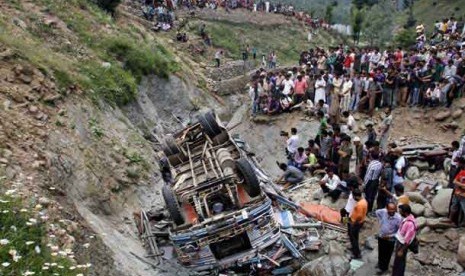  Warga berkerumun menyaksikan bus sekolah yang jatuh di Distrik Baramulla, Kashmir, India, Rabu (11/7).