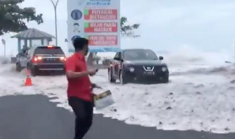 Warga berlari menyelamatkan diri saat gelombang tinggi hantam pesisir Manado dan membuat air laut meluap.