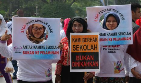 Warga berpose sambil membawa poster 'Stop Perkawinan Anak'.