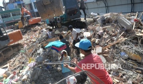 Warga bersama aparat melakukan evakuasi lanjutan di reruntuhan ruko di Pasar Meureudu, Pidie Jaya, NAD, Kamis (8/12).