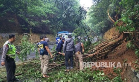 Warga bersama polisi bergotong royong mengevakuasi pohon tumbang yang menutupi ruas jalan Kiaradodot -Cikembulan di Desa Kadungora, Kabupaten Garut.