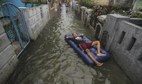 Warga bersantai menggunakan pelampung saat banjir di kawasan Perempatan Mampang, Depok, Jawa Barat, Jumat (19/2/2021). Hujan deras yang mengguyur kawasan membuat aliran kali meluap diperparah sistem drainase yang buruk menyebabkan banjir hingga ketinggian 50 cm