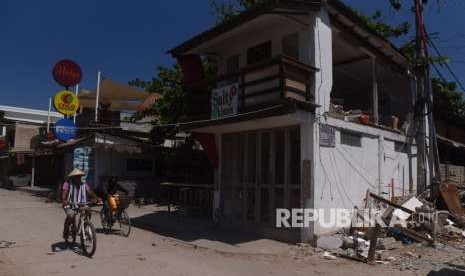 Warga bersepada di samping bangunan yang rusak akibat gempa bumi di Gili Trawangan, Lombok Utara, NTB, Kamis (9/8).