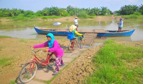 Warga bersiap menaiki perahu untuk menyeberangi Sungai Wulan di Desa Undaan Kidul, Kudus, Jawa Tengah, Senin (6/6/2022). Transportasi perahu penyeberangan yang sudah beroperasi selama puluhan tahun tersebut digunakan warga sebagai lintasan alternatif untuk mempersingkat jarak tempuh antara Kabupaten Kudus dengan Kabupaten Demak karena belum adanya jembatan.