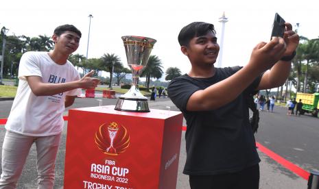 Warga berswafoto di dekat trofi Piala FIBA Asia 2022 yang sedang di pamerkan di area Monas, Jakarta, Rabu (6/7/2022). Trofi Piala FIBA Asia 2022 akan dipamerkan di beberapa lokasi di Jakarta dalam rangkaian tur trofi pada 5-9 Juli sebagai sosialisai ke masyarakat agenda kejuaraan bola basket Piala FIBA Asia 2022 yang digelar di Jakarta pada 12-24 Juli.