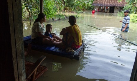 Warga bertahan di depan rumah mereka yang tergenang banjir (Ilustrasi) 