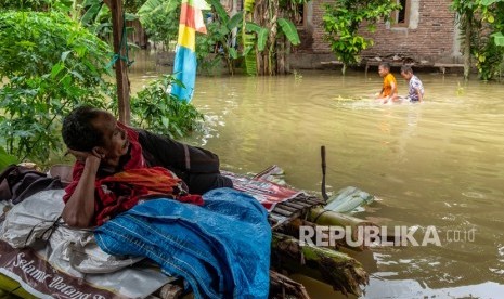  Pengungsi Banjir Demak Mulai Mendapatkan Trauma Healing. Foto: Warga bertahan di depan rumahnya yang terendam banjir akibat Sungai Tuntang jebol di Desa Trimulyo, Guntur, Kabupaten Demak, Jawa Tengah, Jumat (10/1/2020). 