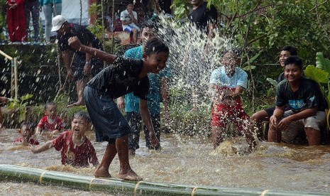  Warga berusaha melewati jembatan bambu diatas kolam untuk mendapatkan hadiah dalam permainan Rarakaan di Dusun Bantarkaler, Desa Darmaraja, Ciamis, Jawa Barat, Ahad (14/6). (Antara/Adeng Bustomi)