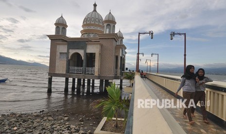 Warga berwisata sambil menunggu datangnya waktu berbuka di Masjid Terapung Arkam Babu Rahman di Pantai Teluk Palu, Sulawesi Tengah, Sabtu (19/5).