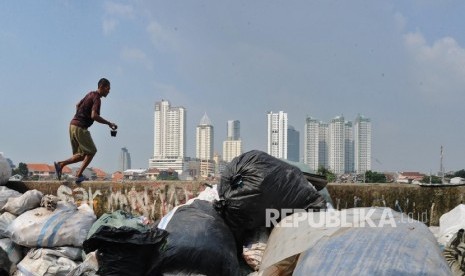 Warga brerjalan saat mengumpulkan sisa produk plastik di Jakarta, Senin (18/7)