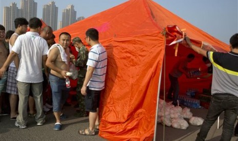 Warga Cina mengantre menerima sarapan karena tidak diizinkan kembali ke rumah mereka dekat lokasi ledakan gudang di Kota Tianjin, Rabu (12/8). 