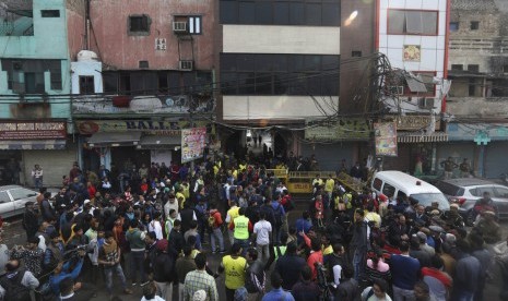 Warga dan petugas berkumpul di luar pasar yang terbakar di New Delhi, India, Ahad (8/12). Sekitar 43 orang meninggal dunia akibat kebakaran tersebut.