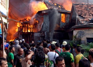 Warga dan petugas pemadam kebakaran berusaha memadamkan api yang membakar permukiman warga di kawasan Jalan Lautze, Jakarta Pusat, Selasa,(7/2). (Republika/Prayogi)