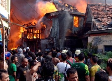 Warga dan petugas pemadam kebakaran berusaha memadamkan api yang membakar permukiman warga di kawasan Jalan Lautze, Jakarta Pusat, Selasa (7/6). 