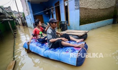 Warga dengan menggunakan perahu karet melintasi banjir di Kampung Bojong Asih, Desa Dayeuhkolot, Kabupaten Bandung, Jawa Barat, Selasa (6/3).