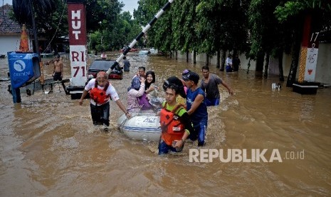 Warga dengan menggunkan perahu karet melintasi banjir akibat luapan Sungai Ciliwung, Bukit Duri, Jakarta, Kamis (16/2). 