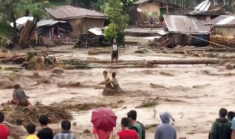 Warga desa mencoba menyeberang banjir di Lanao del Norte, Zamboanga Pennisula, di bagian selatan Filipina, Jumat (22/12). Banjir menjerang kawasan itu akibat badai tropis.