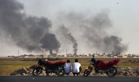 Warga di Provinsi Akcakale Sanliurfa, tenggara Turki yang berbatasan dengan Suriah menyaksikan asap membumbung di wilayah Suriah yang dibombardir pasukan Turki, Kamis (10/10). Turki melakukan operasi militer di perbatasan dengan Suriah.