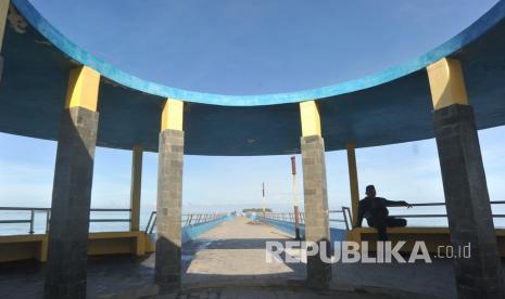 Warga duduk di Dermaga Pantai Gandoriah yang sepi di Pariaman, Sumatera Barat, Senin (25/5/2020). Pemkot Pariaman menutup semua objek wisata pantai di kota Tabuik itu selama libur lebaran karena masih dalam masa PSBB hingga 29 Mei 2020. 