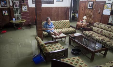 Warga duduk dikursi saat rumahnya tergenang air akibat banjir di Kampung Timuran, Solo, Jawa Tengah, Ahad (8/5/2022). Banjir tersebut terjadi karena hujan deras serta meluapnya Kali Senggol akibat buruknya sarana drainase.