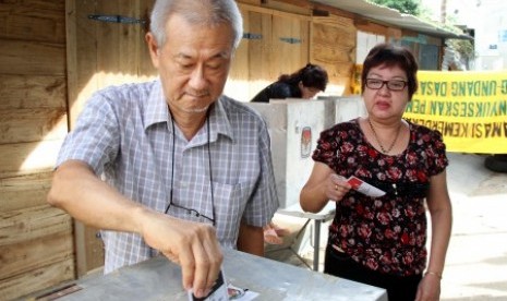 Warga etnis Tionghoa memasukkan kertas surat suara kedalam kota suara saat menggunakan hak pilihnya pada pemungutan suara Pemilu Presiden/wakil Presiden 2014 