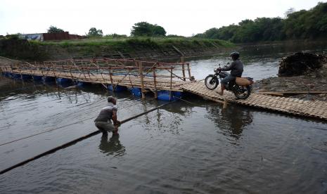 Warga Gadingan, Sukoharjo Bagong (kiri) membuat jembatan bambu (sesek) di atas Sungai Bengawan Solo yang menghubungkan Desa Mojolaban, Sukoharjo dengan Kampung Sewu di Solo, Jawa Tengah, Kamis (8/9/2022). Jembatan bambu tersebut dibuat sebagai jalan alternatif warga setempat untuk mempersingkat jarak waktu perjalanan menyusul akan ditutupnya sejumlah jalan utama di Solo dan Sukoharjo guna perbaikan. 