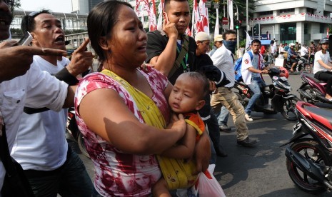 Warga ibu-ibu mengendong anak sambil menanggis saat bentrokan terjadi di Jl Thamrin, Jakarta, Kamis (21/8). Massa pendukung Prabowo-Hatta sempat terjadi bentrokan dengan petugas keamanan, dan sempat ditembakkan gas air mata.