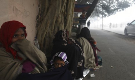 Warga India membungkus diri mereka dengan jaket dan selimut di tengah kabut di New Delhi, India, Senin (30/12). Kabut tebal menyelimuti India utara dengan suhu mencapai titik rendah. 