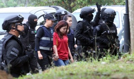 Warga Indonesia Siti Aisyah (berkaus merah) dengan dikawal polisi bersenapan otomatis saat akan masuk ke Pengadilan Sepang di Sepang, Malaysia, Rabu (1/3). Bersama perempuan Vietnam, ia diduga membunuh warga Korea Utara Kim Jong-nam.