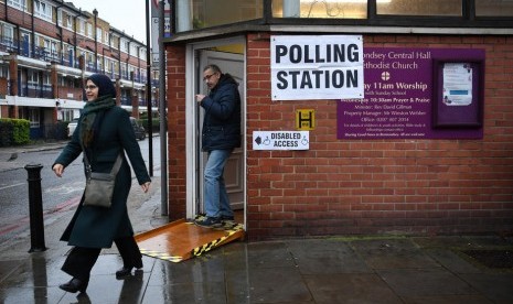 Warga Inggris di London bagian selatan keluar dari tempat pemungutan suara usai memberikan suaranya dalam Pemilu pada Kamis (12/12).