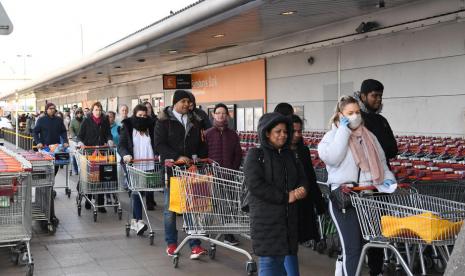 Warga Inggris mengantre di sebuah supermarket di London, Inggris, Ahad (22/3). 