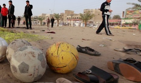 Warga Irak berjalan di bekas ledakan bom di kota Shula, Irak 